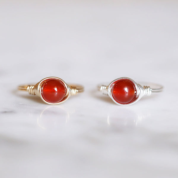 photo of two carnelian gemstone rings made with gold and silver side by side