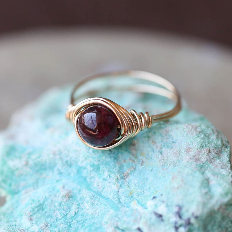 a photo of a garnet gemstone ring sitting on a beatiful rock.