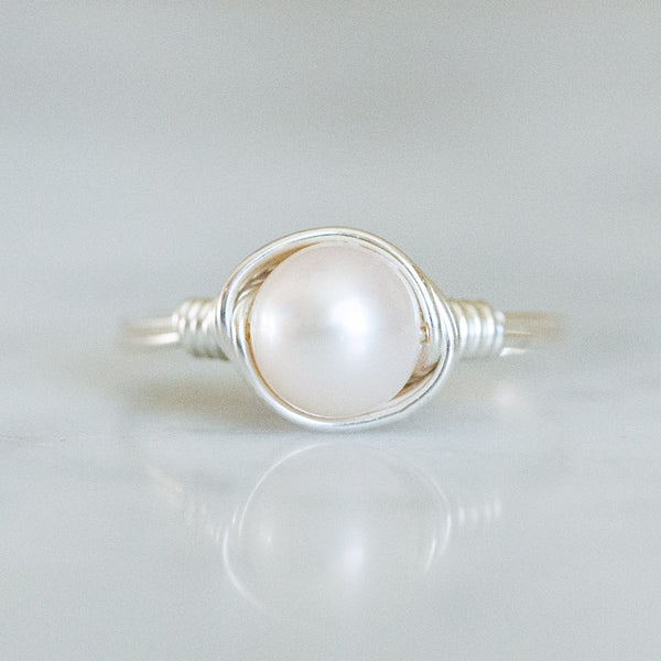 a photo of a pearl ring in solitaire setting wrapped in sterling silver wire